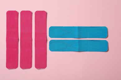 Photo of Bright kinesio tape pieces on pink background, flat lay