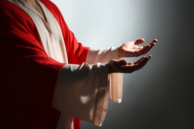 Jesus Christ reaching out his hands on grey background, closeup