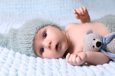 Photo of Cute newborn baby with crochet toy on light blue blanket