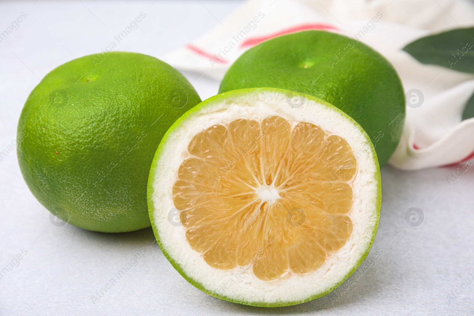 Photo of Whole and cut sweetie fruits on white table, closeup