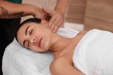 Photo of Woman receiving professional neck massage on couch indoors