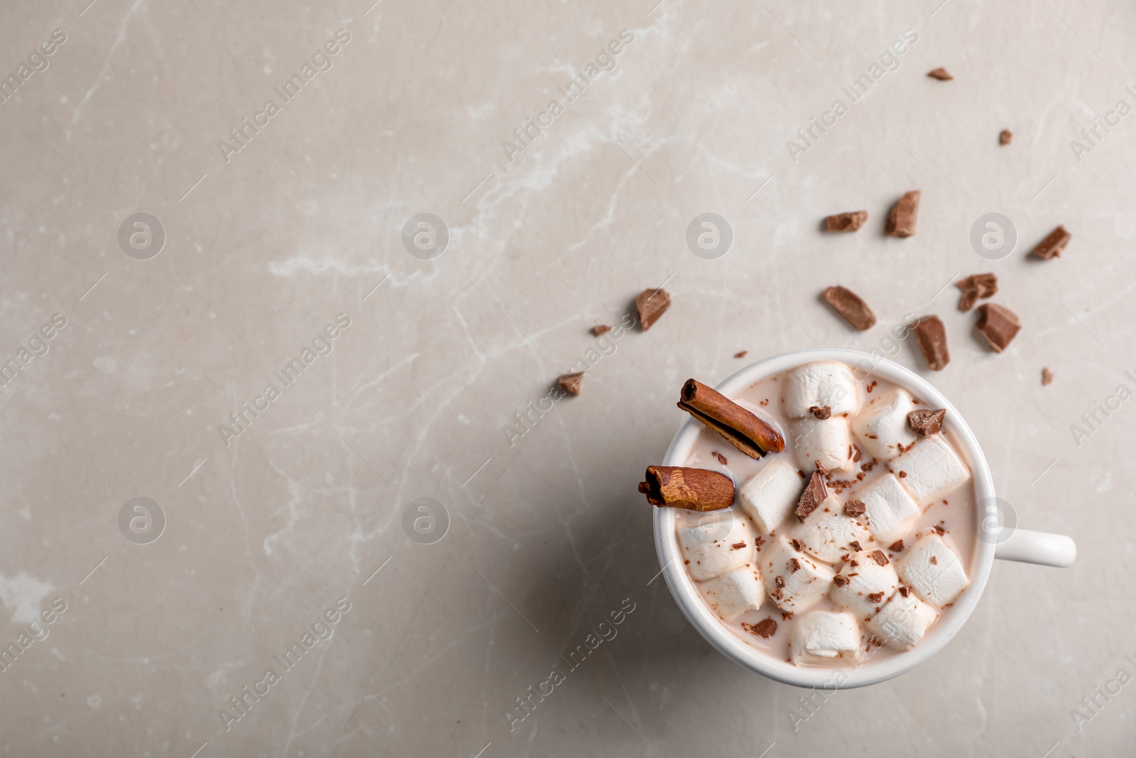 Photo of Tasty hot chocolate with milk and marshmallows in cup on table, top view. Space for text