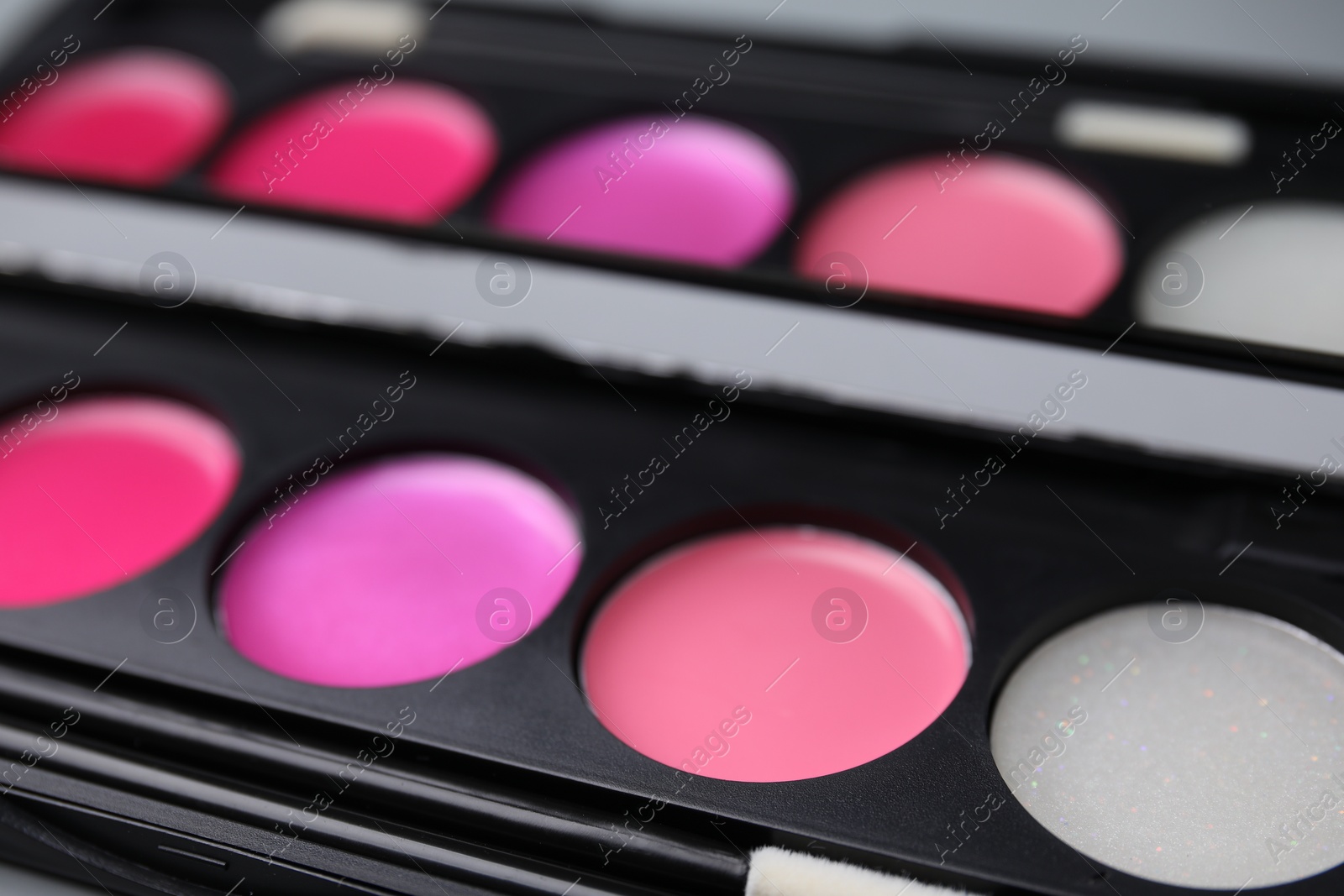 Photo of Colorful lip palette with brush as background, closeup. Professional cosmetic product