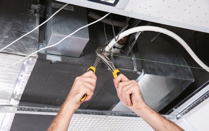 Photo of Young male technician repairing air conditioner indoors