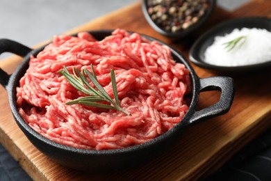 Photo of Raw ground meat in bowl and spices on table, closeup