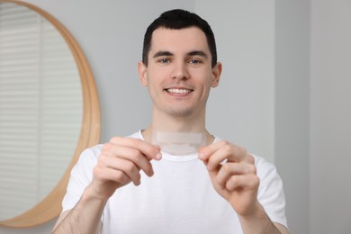 Young smiling man with whitening strips indoors