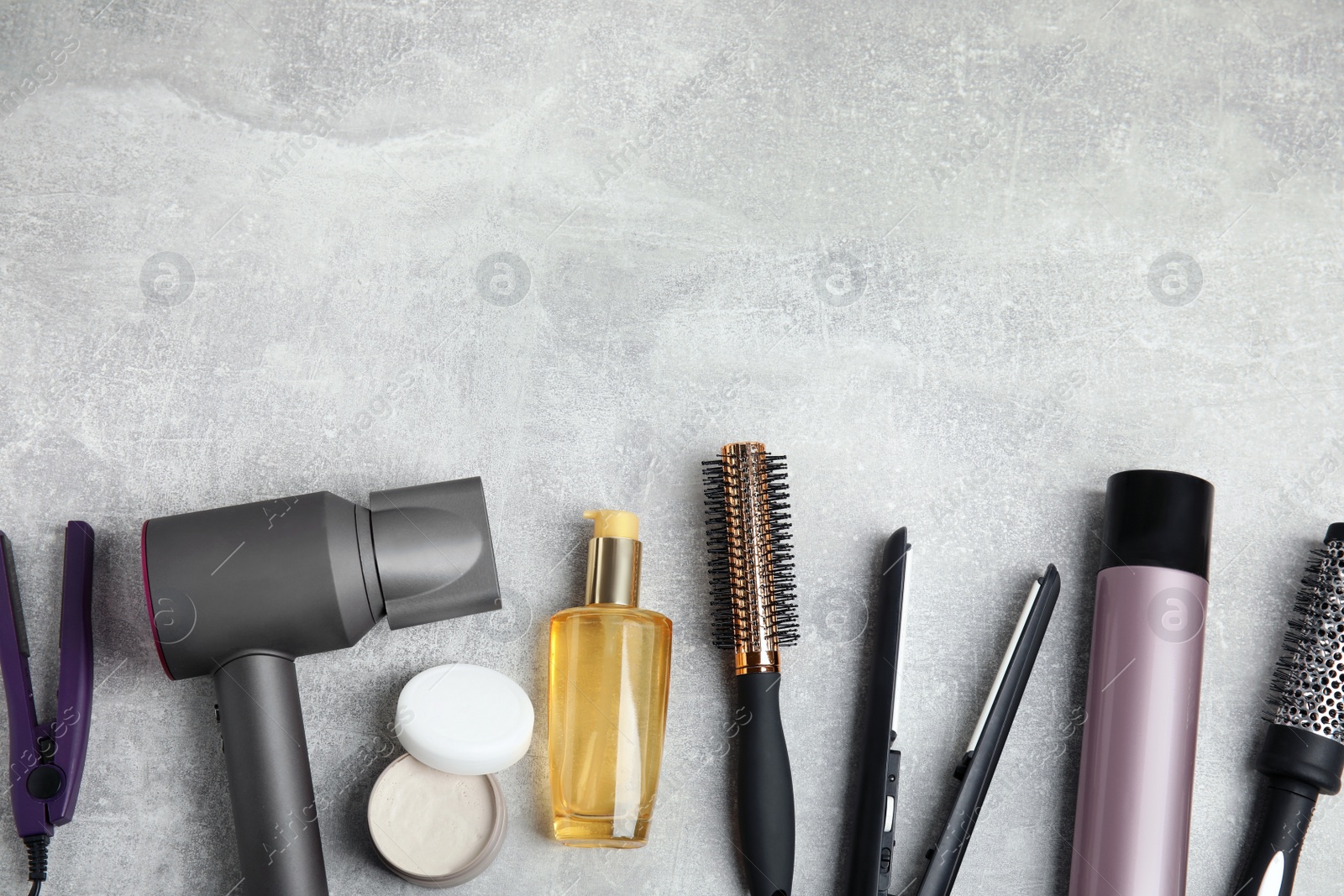 Photo of Flat lay composition with hairdressing equipment on grey stone background. Space for text