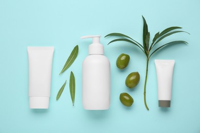 Photo of Cosmetic products with olive essential oil on light turquoise background, flat lay