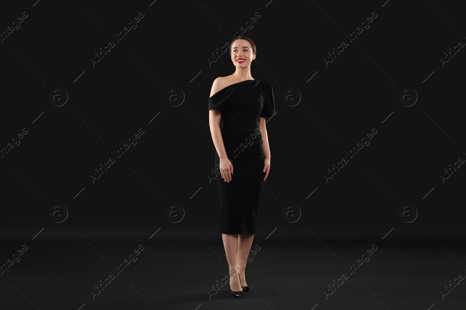 Photo of Beautiful young woman in elegant dress on black background