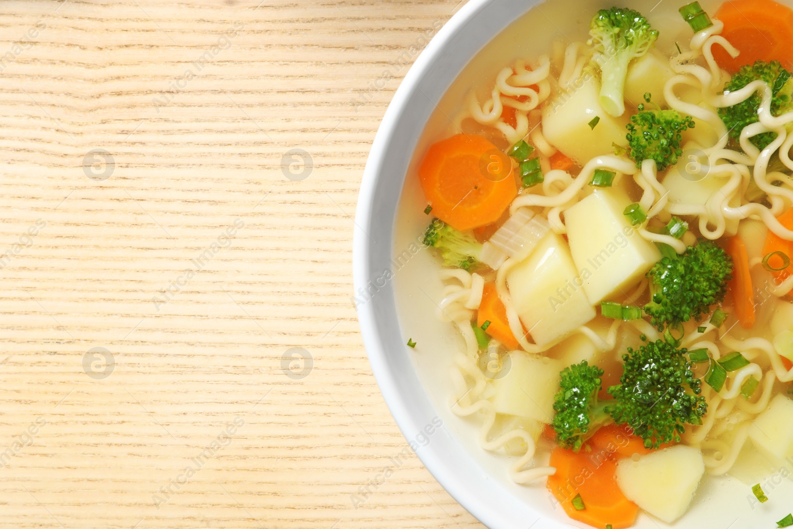 Photo of Bowl of fresh homemade vegetable soup on wooden background, top view. Space for text