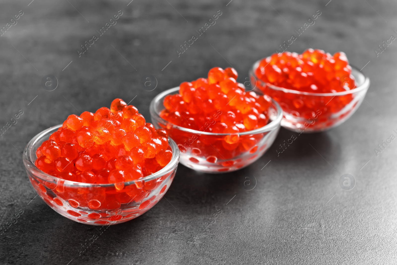 Photo of Glass bowls with delicious red caviar on table