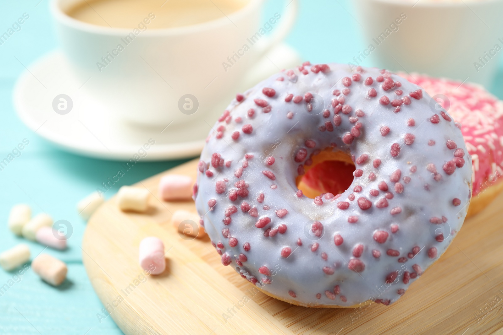 Photo of Delicious glazed donuts on blue wooden table, closeup