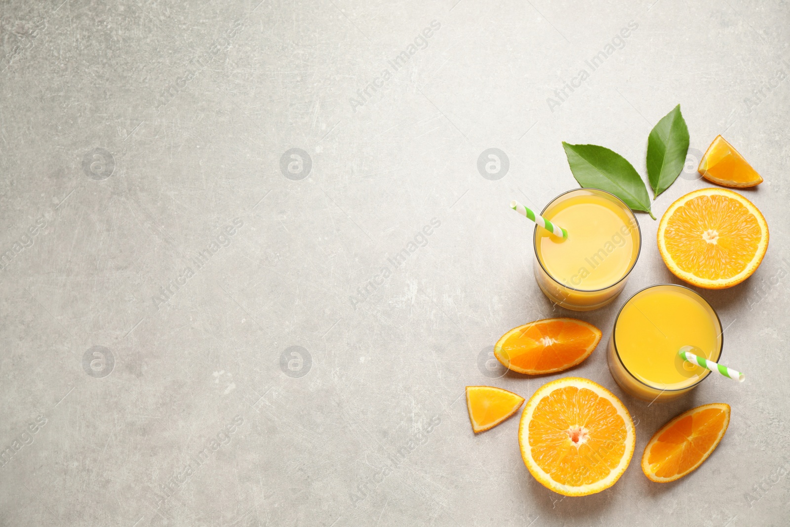 Photo of Glasses of orange juice and fresh fruits on light grey table, flat lay. Space for text