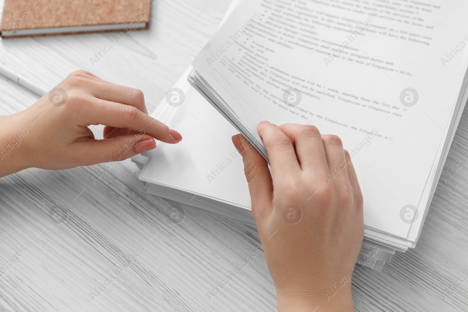 Photo of Woman reading documents at white wooden table in office, above view