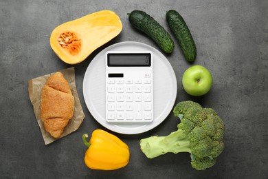 Photo of Calculator and food products on dark grey table, flat lay. Weight loss concept