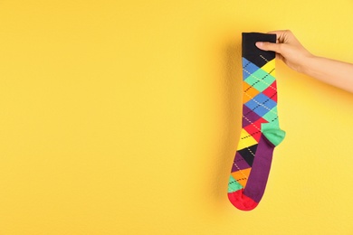 Photo of Woman holding bright sock and space for design on color background