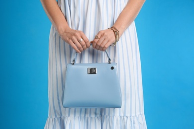 Young woman with stylish bag on light blue background, closeup