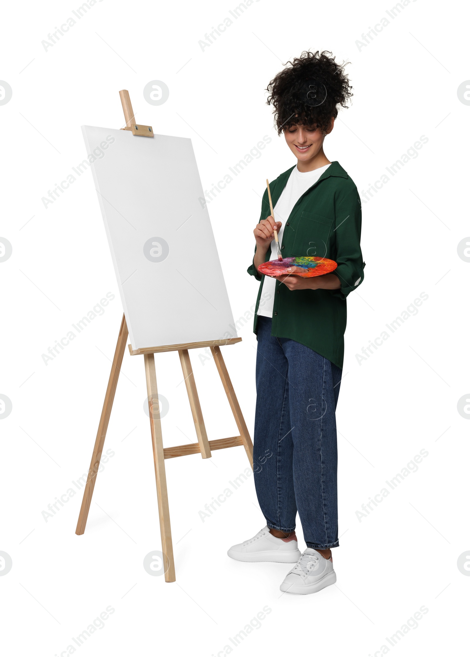 Photo of Young woman painting on easel with canvas against white background