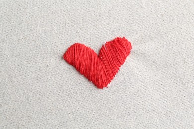 Photo of Embroidered red heart on light cloth, top view