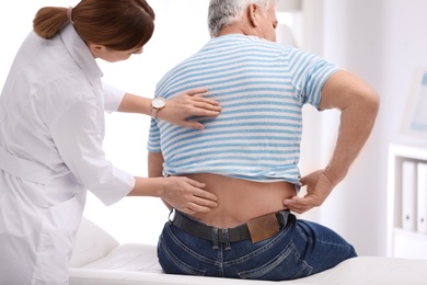 Chiropractor examining patient with back pain in clinic