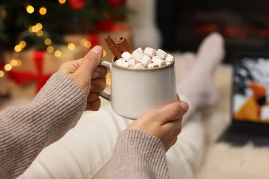 Photo of Woman drinking delicious cocoa and watching Christmas movie at home, closeup