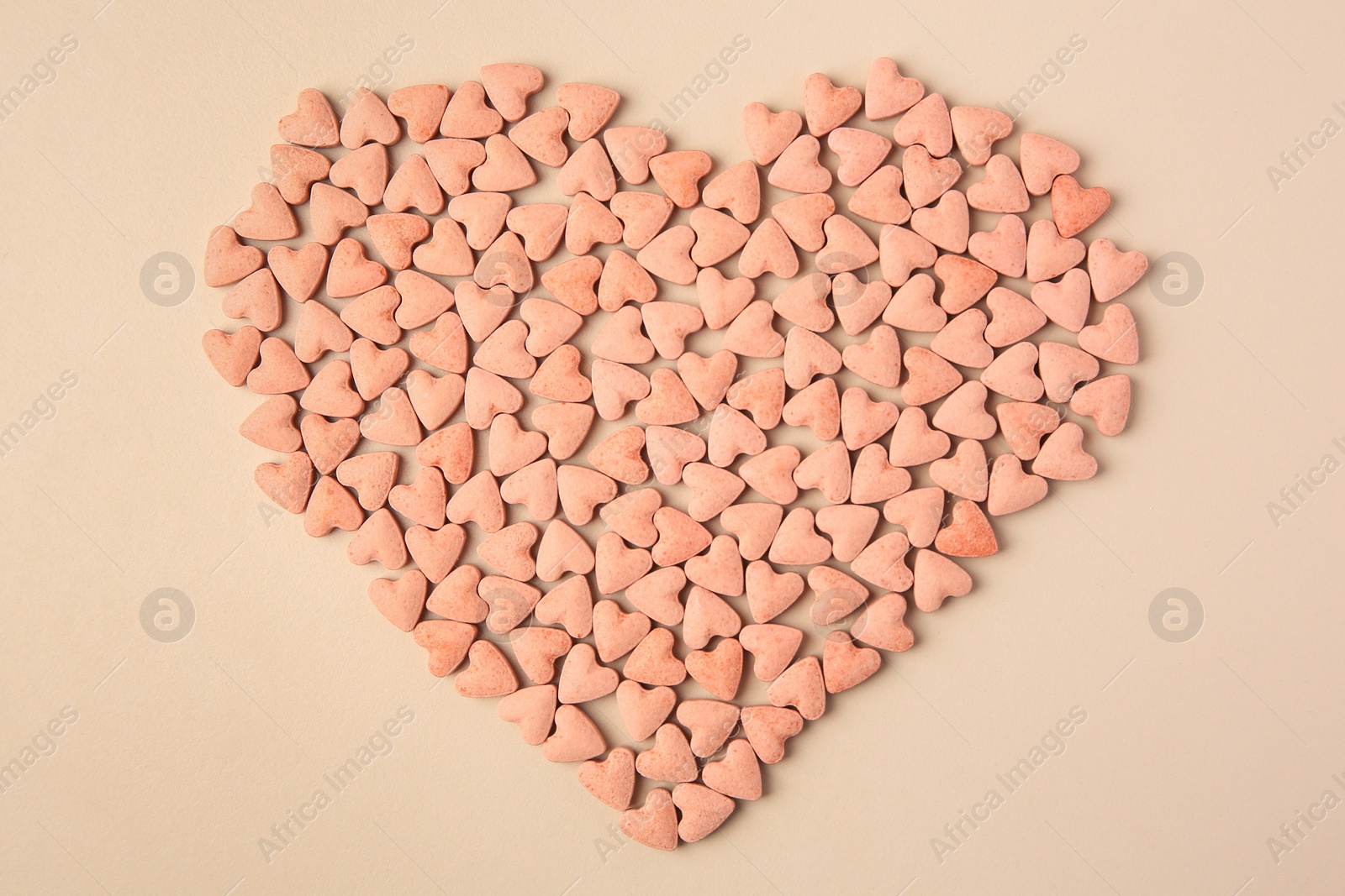 Photo of Heart made of vitamins for pets on beige background, top view