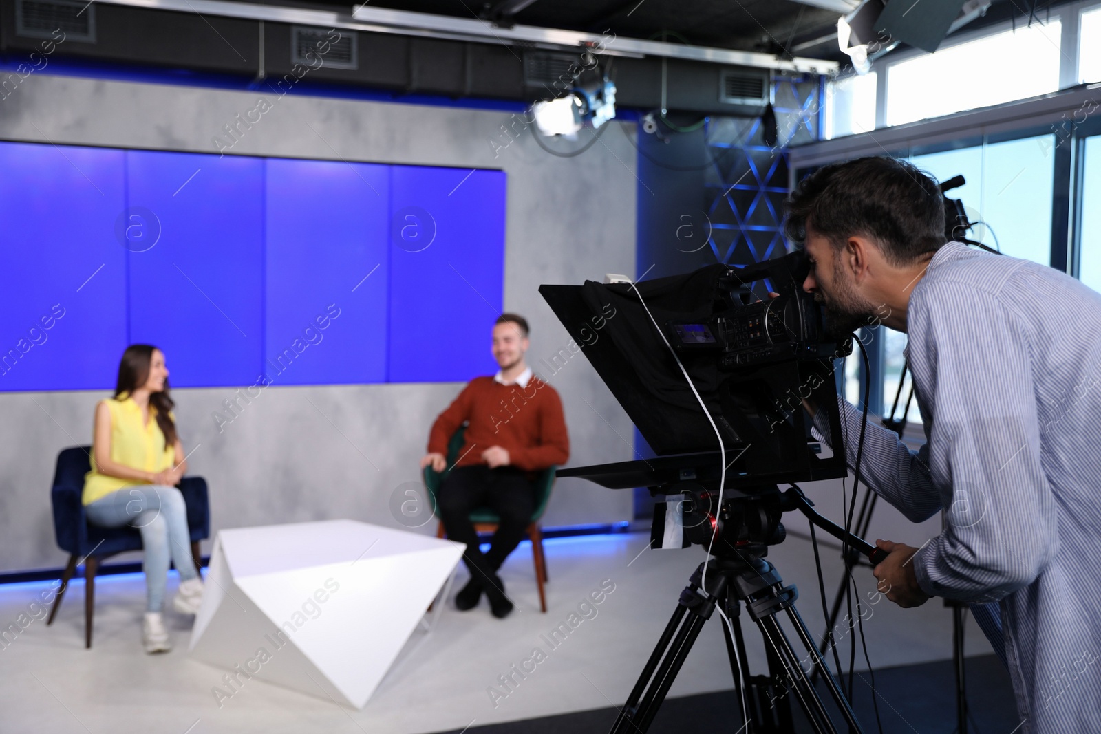 Photo of Presenters and video camera operator working in studio. News broadcasting