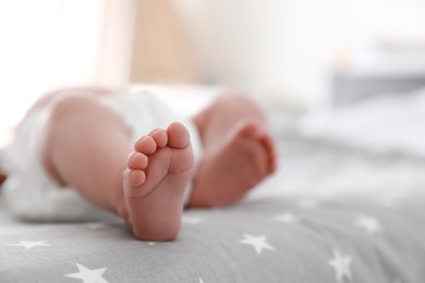 Photo of Cute little baby lying on bed at home, closeup of legs