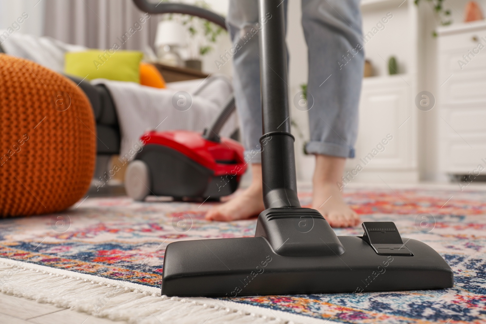 Photo of Woman cleaning carpet with vacuum cleaner at home, closeup