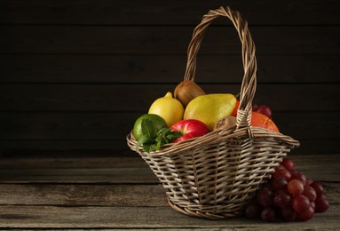 Fresh ripe fruits in wicker basket on wooden table, space for text