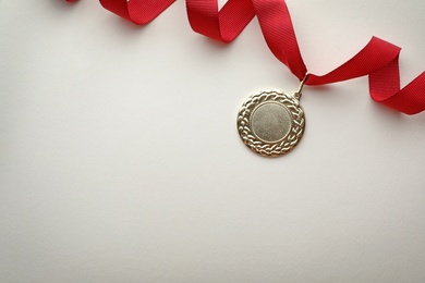 Photo of Gold medal on white background, top view with space for text. Symbol of victory