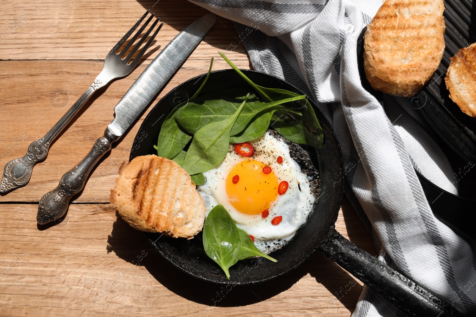 Photo of Delicious fried egg with spinach and chilli served on wooden table, flat lay