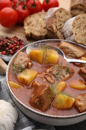 Photo of Delicious goulash in bowl on dark wooden table, closeup