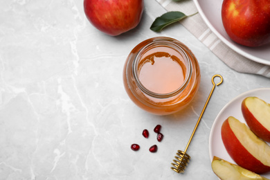 Photo of Honey, apples and pomegranate seeds on light grey marble table, flat lay with space for text. Rosh Hashanah holiday