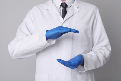 Photo of Dentist holding something on light grey background, closeup