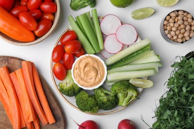 Photo of Plate with delicious hummus and fresh vegetables on white table, flat lay