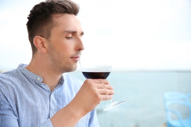 Young man with glass of red wine outdoors