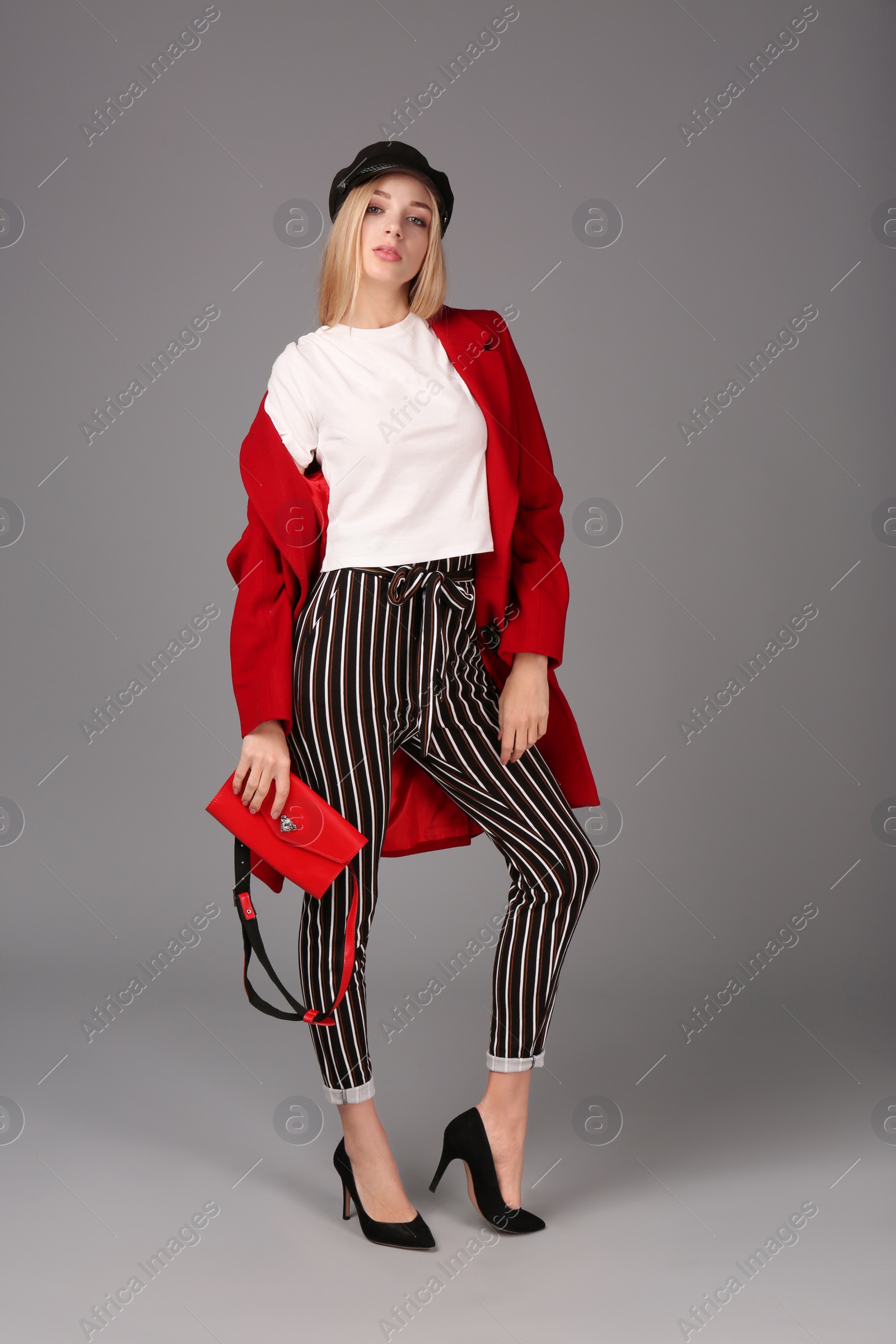 Photo of Young stylish woman in trendy shoes with bum bag on grey background