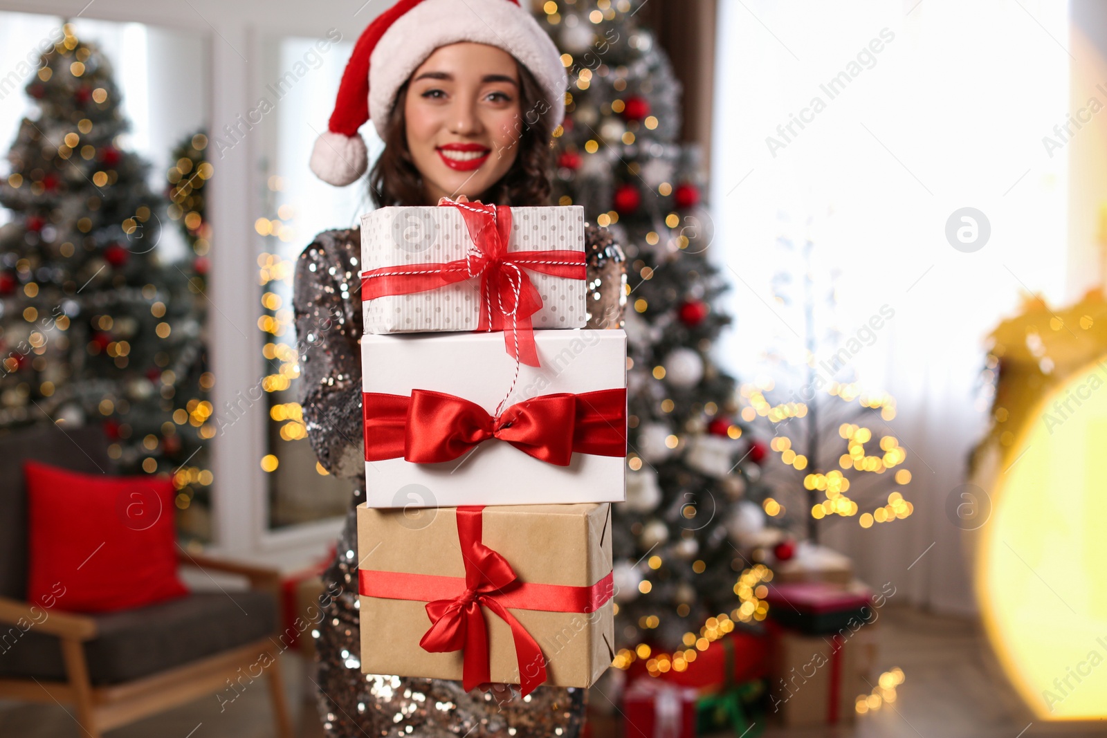 Photo of Beautiful woman in Santa hat with Christmas gifts at home