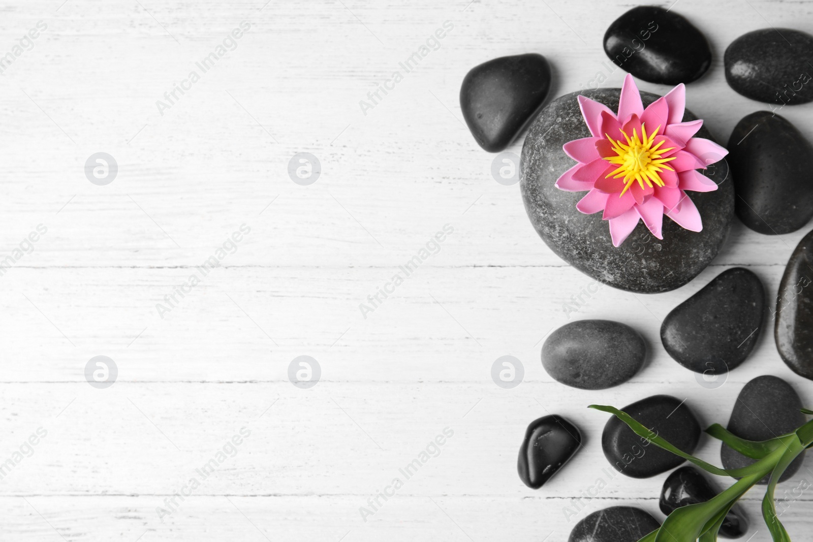 Photo of Stones, bamboo, lotus flower and space for text on white wooden background, flat lay. Zen lifestyle