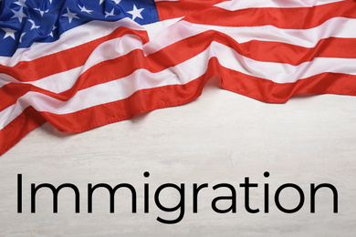 Image of American flag and word IMMIGRATION on white wooden background, top view