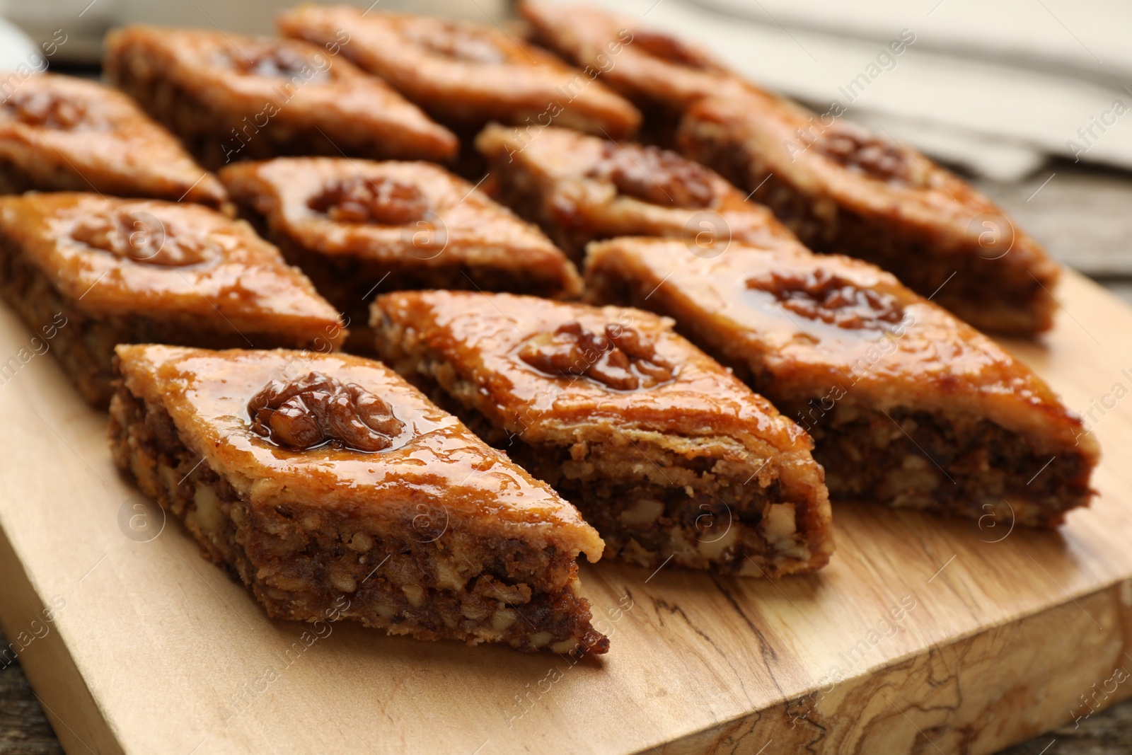 Photo of Delicious sweet baklava with walnuts on wooden board, closeup