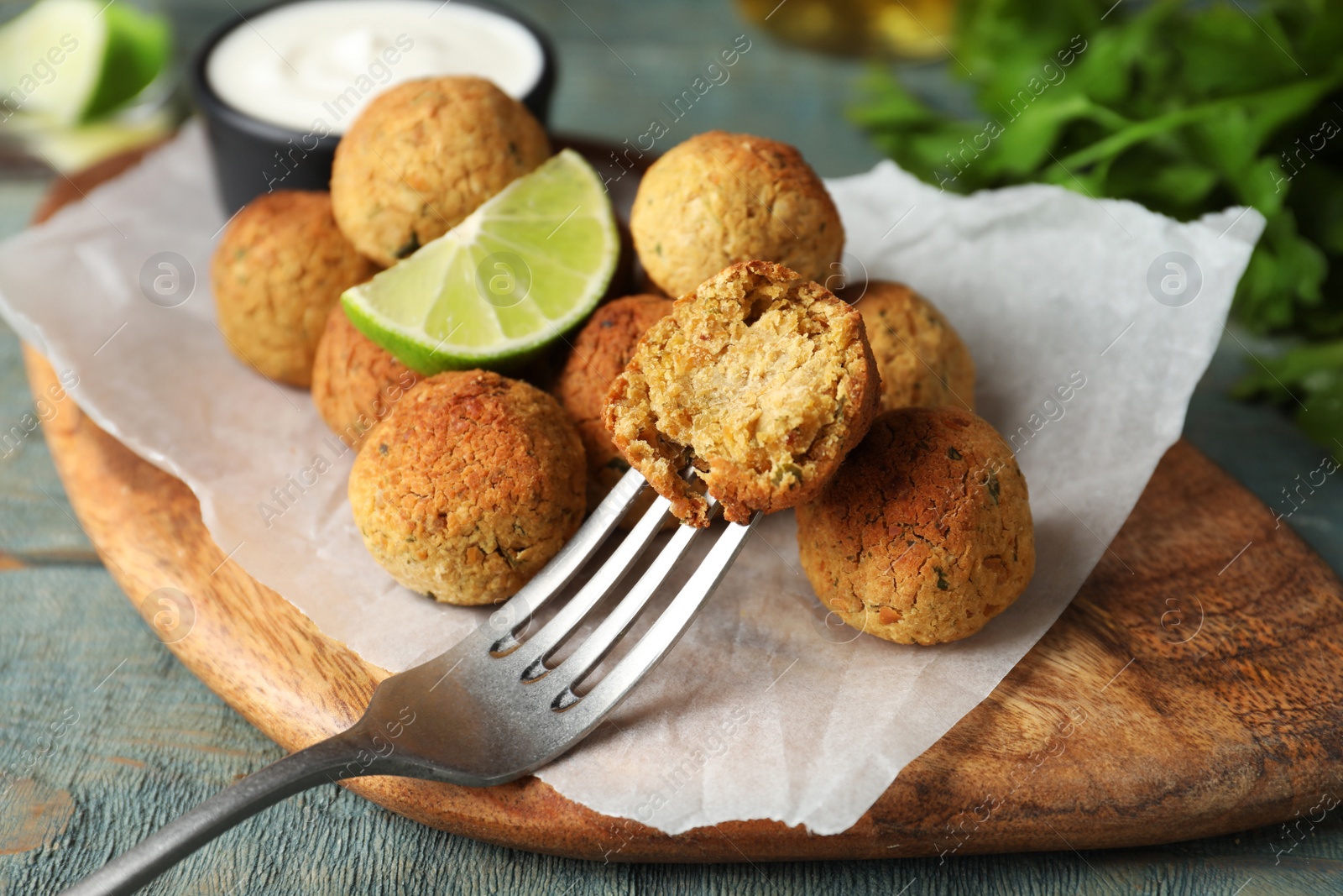 Photo of Delicious falafel balls with lime on light blue wooden table, closeup