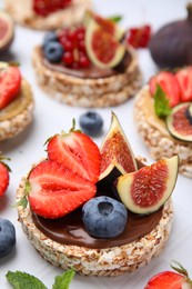 Photo of Tasty crispbreads with chocolate, figs and berries on light table, closeup