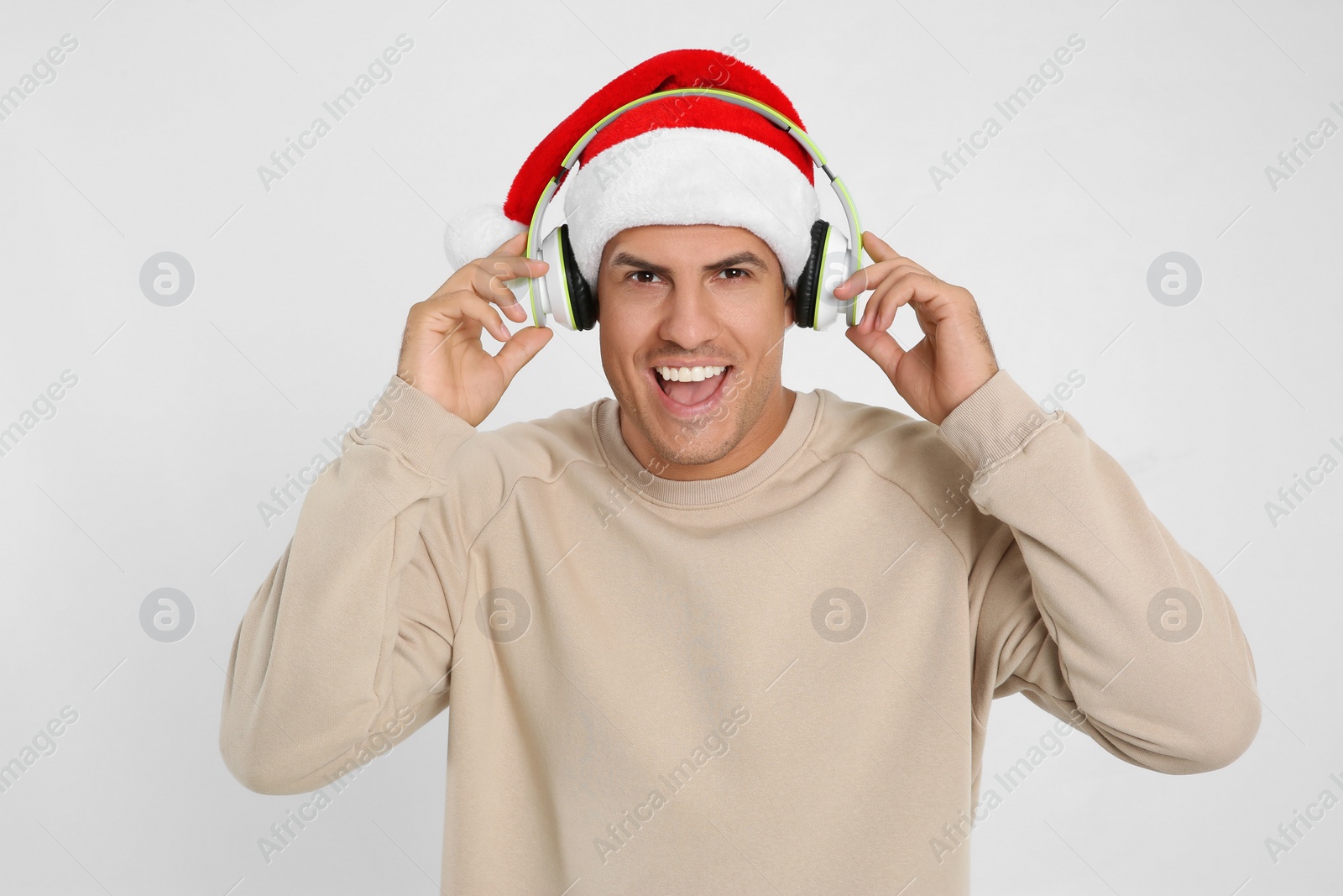 Photo of Emotional man with headphones on white background. Christmas music