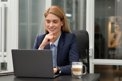 Woman working on laptop at black desk in office