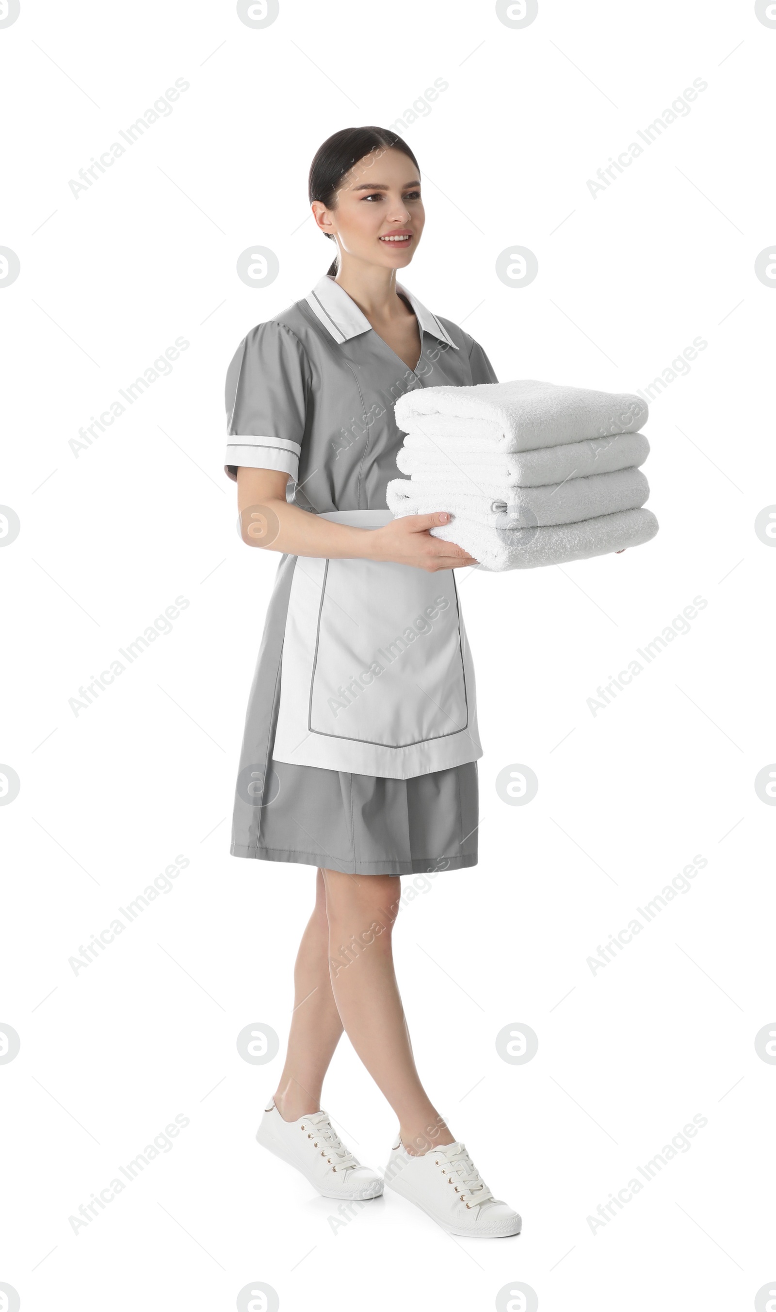 Photo of Young chambermaid holding stack of fresh towels on white background