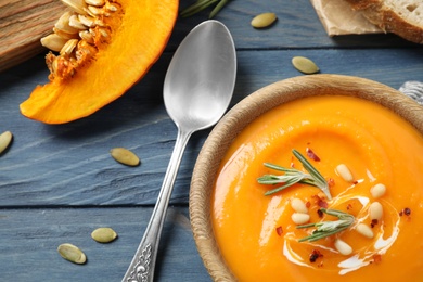 Delicious pumpkin soup in bowl on blue wooden table, flat lay