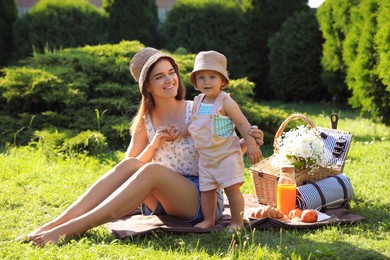 Mother with her baby daughter having picnic in garden on sunny day