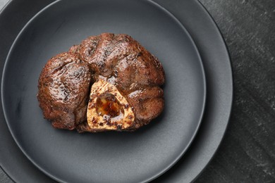 Photo of Piece of tasty grilled beef meat on black table, top view